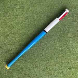 May include: A blue and white baseball bat with black and red accents. The bat has a yellow tip.