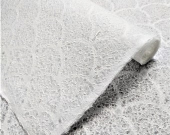 Puede incluir: Primer plano de un rollo de papel blanco texturizado. El papel tiene una superficie rugosa y desigual.