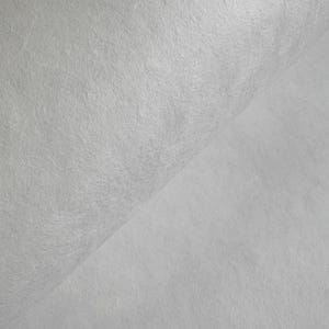 Puede incluir: Primer plano de una tela texturizada de color blanco roto. El material est&aacute; doblado, creando un efecto de capas. La superficie tiene un aspecto ligeramente rugoso y fibroso, con sutiles variaciones tonales. La tela parece suave.