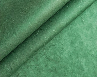 May include: Green textured paper with a subtle, mottled appearance. The paper is folded in half, creating a diagonal crease.