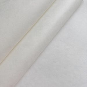 Puede incluir: Primer plano de una tela blanca rota doblada. El material parece suave y texturizado, con sutiles variaciones de tono. Los pliegues crean sombras y profundidad, resaltando la delicada naturaleza de la tela. La impresi&oacute;n general es de textura suave y color neutro.