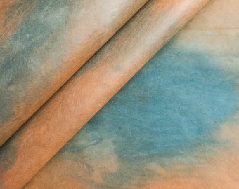 May include: A close-up of a folded piece of paper with a blue, orange, and brown tie-dye pattern.