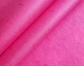 May include: Close-up of a bright pink textured paper. The paper is folded in half, creating a diagonal line across the image.