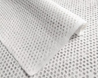 Puede incluir: Papel blanco con un patrón texturizado de panal de abeja. El papel está doblado por la mitad, mostrando el patrón en ambos lados.