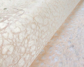 May include: Close-up of a sheet of white textured paper with a delicate, woven pattern. The paper is folded over, revealing a similar sheet of paper with a slightly different texture.