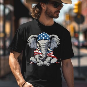 May include: A black t-shirt with a graphic of an elephant wearing a bandana with the American flag pattern. The elephant is sitting with its legs crossed and is holding the American flag in its trunk.