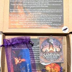 May include: A purple pouch with a card inside that reads "Burn Bag" and a card with a bonfire image and the text "Samhain Bonfire Blend A Magical Mix for the Darkest Night". The pouch is sitting on a brown surface with a small bag of dried herbs and flowers.