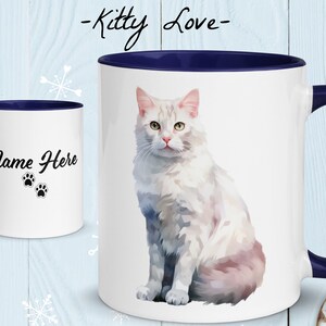 May include: White ceramic mug with a blue rim and handle. The mug features a white cat with pink accents sitting on a white background. The text "Kitty Love" is printed in black at the top of the mug. The text "Name Here" is printed in black on the other side of the mug, along with two black paw prints.