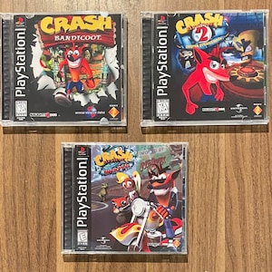 May include: Three PlayStation game cases featuring Crash Bandicoot. The games are "Crash Bandicoot", "Crash Bandicoot 2: Cortex Strikes Back", and "Crash Bandicoot: Warped". Each case has vibrant artwork and the PlayStation logo.