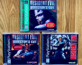 May include: Three PlayStation video game cases for Resident Evil Director's Cut. The cases are black with red and white text. The first case has a green PlayStation Greatest Hits logo. The second case has a zombie character on the cover. The third case has a character holding a gun.