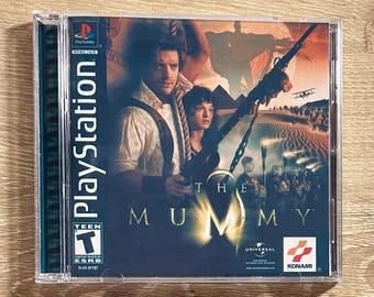 May include: A PlayStation game case for "The Mummy" featuring actors and desert scenery. The case includes the PlayStation logo, ESRB rating, and the Universal and Konami logos.