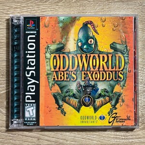 May include: A PlayStation video game case for Oddworld: Abe's Exoddus. The cover features a green creature with a stitched mouth against an orange background with bubbles. Text includes the title, the ESRB Teen rating, and GT Interactive Software.