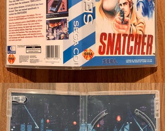 May include: A Sega CD game case for the game Snatcher. The case is blue and white with a picture of the game's characters on the front. The back of the case has a description of the game. The game is rated for mature audiences.
