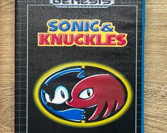 May include: A blue plastic Sega Genesis video game case for Sonic & Knuckles. The black cover features the game title in blue and red text, a circular graphic of Sonic and Knuckles, a Lock-On Technology logo, and a GA rating symbol for general audiences.
