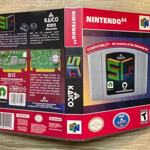 May include: A gray Nintendo 64 game cartridge with a colorful logo and the text "KAICO" and "64". The packaging includes the text "NINTENDO 64" and "COMPATIBILITY". The game cartridge is in a clear plastic case.
