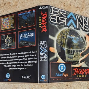 May include: A retro Atari Jaguar video game cartridge case for "Brawn and Brains." The case features game screenshots, the AtariAge logo, and the Jaguar logo. The cover art shows a globe-like object with a futuristic design.