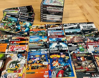 May include: A collection of PlayStation 2 video game cases and manuals arranged in a stack and spread out across a surface. The items feature various colorful graphic art, game titles, and logos, including Crash Tag Team Racing and Dragon Ball Z.