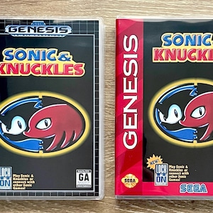 May include: Two Sega Genesis video game cases for Sonic & Knuckles. Both feature black covers with the title in yellow and red, and a central circular graphic showing Sonic and Knuckles. Each case includes the Lock-On technology logo and GA rating.