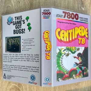 May include: Atari 7800 video game cartridge for Centipede TB. The game case features the text "This Game's Got Bugs!" and a colorful illustration of a centipede and a figure. The game is programmed by Ken Siders.