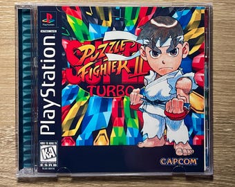 May include: Puzzle Fighter II Turbo PlayStation game case. The cover features a cartoon character in a karate uniform with a determined expression. The game title is in a vibrant, colorful design. The PlayStation logo is visible.