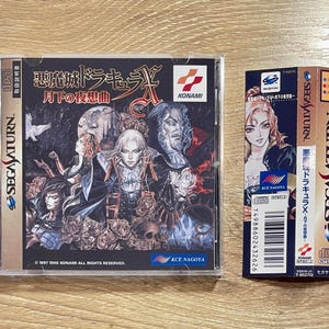 May include: Two Sega Saturn video game cases. The larger case features the title "Castlevania: Symphony of the Night" in Japanese and English, with character art. The smaller case is a vertical box with the title "Dracula X" and character art.