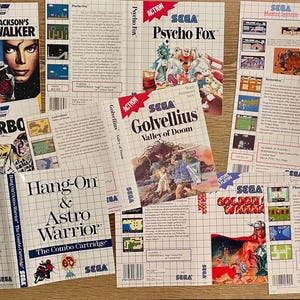 May include: A collection of Sega Master System game boxes and inserts, including titles like "Michael Jackson's Moonwalker," "Paperboy," "Psycho Fox," and "Phantasy Star." The boxes feature colorful game art and the Sega logo.
