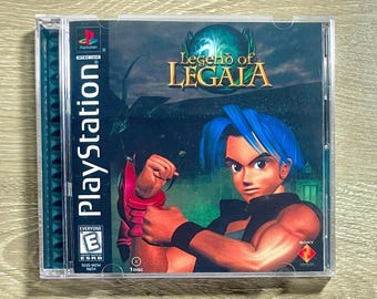 May include: A PlayStation game case for "Legend of Legaia." The cover art features a character with blue hair and a determined expression. The game case is in a clear plastic case with the PlayStation logo and ESRB rating visible.