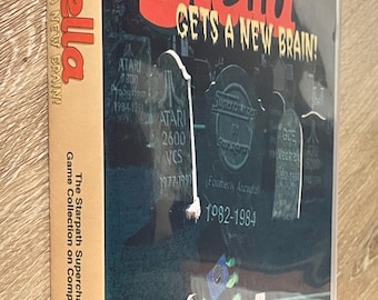 May include: A compact disc case for the video game "Stella Gets a New Brain!" The cover features the title in red, with a graveyard scene. The case also includes the text "The Starpath Supercharger Game Collection on Compact Disc."