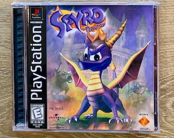 May include: A purple and yellow Spyro the Dragon PlayStation game case with a purple dragon on the front. The game is rated E for Everyone by the ESRB.