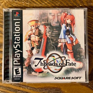 Może przedstawiać: Pudełko gry PlayStation do Threads of Fate, gry RPG od SquareSoft. Pudełko zawiera kolorową ilustrację dwóch postaci, jedna w czerwono-niebieskim stroju, a druga w żółto-brązowym stroju. Gra jest oceniona przez ESRB jako E dla wszystkich.