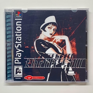 Puede incluir: Una caja de juego de PlayStation con un fondo negro y una mujer con un sombrero blanco y un atuendo negro. El título del juego es "thrill kill" en letras blancas. El juego está clasificado como "AO" para adultos únicamente por la ESRB.