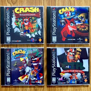 Op de afbeelding: Vier PlayStation-speldozen met Crash Bandicoot. De dozen zijn zwart met een kleurrijk beeld van Crash Bandicoot op de voorkant. De titels zijn Crash Bandicoot, Crash Bandicoot 2: Cortex Strikes Back, Crash Bandicoot: Warped en Crash Team Racing.
