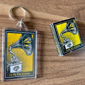 May include: A black and yellow keychain with a vintage gramophone design and the text "Third Man Records".