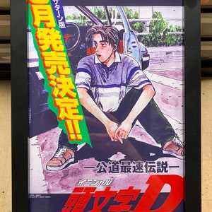 May include: A framed poster for the Japanese manga series Initial D. The poster features a young man sitting on the ground next to a car. The poster is in Japanese and English and says "Initial D" and "Public Road Fastest Legend".