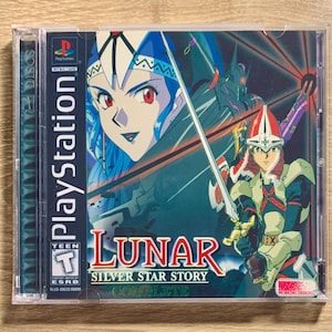 May include: A PlayStation game case with a blue and white background. The game is called "Lunar: Silver Star Story Complete". The case has a Teen rating from the ESRB.