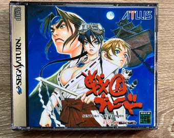 May include: A Sega Saturn video game case for Sengoku Ace Episode II featuring anime-style character illustrations against a dark blue night sky with a full moon and a castle silhouette. The cover includes the Atlus logo and Japanese text.