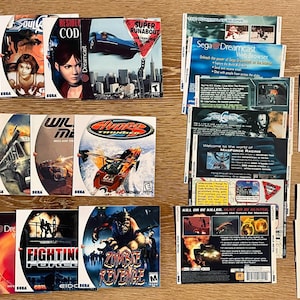 May include: A collection of Sega Dreamcast game discs and inserts, featuring titles like "Grand Theft Auto", "Resident Evil: Code Veronica", and "Soul Calibur". The game covers display various action and adventure themes, with vibrant graphics and logos.