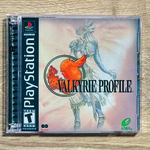 May include: A PlayStation video game case for Valkyrie Profile, featuring a warrior illustration, the PlayStation logo, an ESRB Teen rating, and the Enix logo. The cover art displays a character in armor with a large orange emblem and text.