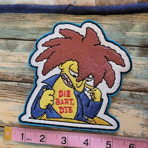 May include: Embroidered patch featuring Sideshow Bob from The Simpsons, with red hair, a blue jacket, and the text "Die Bart Die". The patch is outlined in blue and measures approximately 3 inches in length.