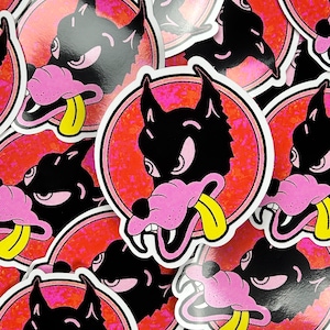 May include: A stack of colourful stickers featuring a cartoon wolf with a pink nose and tongue sticking out. The wolf is outlined in black and set against a red background with a white circle around it.