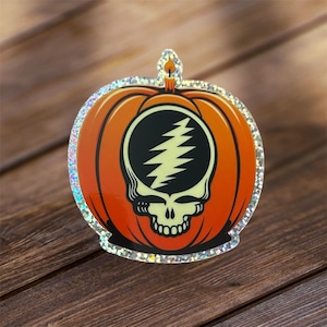 May include: A sparkly orange pumpkin with a black and white Grateful Dead Steal Your Face logo. The pumpkin has a candle on top.