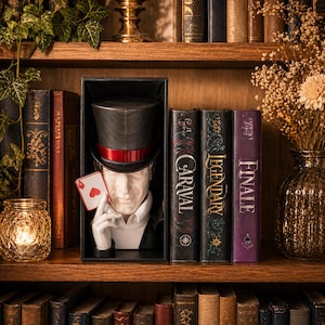 Può includere: Busto di mago con cilindro e carta da gioco, esposto su una libreria con libri decorativi. Il busto è bianco con un cilindro nero e una fascia rossa. La carta è l'Asso di Cuori.