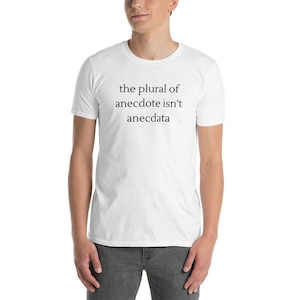 May include: White short-sleeved t-shirt with the black text: "the plural of anecdote isn't anecdota". The shirt is made of a soft material. The t-shirt is being worn by a person.
