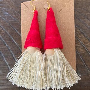 May include: A pair of red felt gnome earrings with white yarn beards and gold hooks.