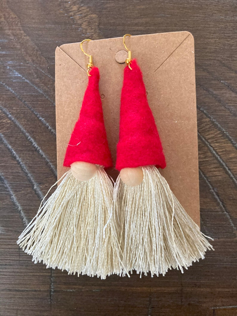 May include: A pair of red felt gnome earrings with white yarn beards and gold hooks.