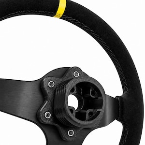 May include: A black steering wheel with a yellow center marker at the top, featuring black stitching and a central mounting hub. The text BALTIC MOTORSPORT SOLUTIONS is visible at the top with a thin yellow, green, and red line underneath.