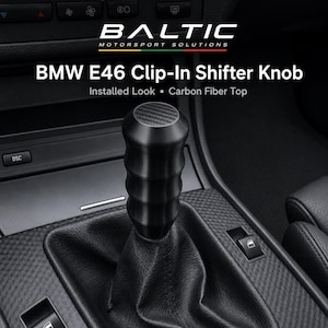 Può includere: Un pomello del cambio cilindrico nero con un inserto superiore in fibra di carbonio, installato nella console centrale di un veicolo. Il testo BALTIC MOTORSPORT SOLUTIONS, BMW E46 Clip-In Shifter Knob, Installed Look e Carbon Fiber Top è visibile.