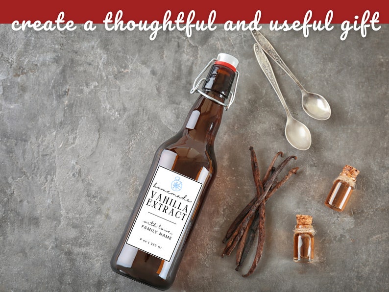 May include: A brown glass bottle with a white label that reads "Homemade Vanilla Extract with love, FAMILY NAME" and a compass design. The bottle is sitting on a gray surface with vanilla beans, two small bottles of vanilla extract, and two silver spoons.