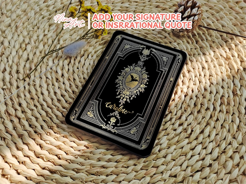 May include: A black book cover with gold accents and a floral design. The book cover has the name "Caroline" written in gold script.