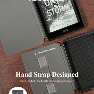 Op de afbeelding: Een grijze Kindle-hoes met een handriemontwerp, open getoond met een Kindle-apparaat erin. De hoes heeft de tekst "Hand Strap Designed" en "leave you hold the kindle more easily and safety". De Kindle toont de boekomslag "ON STORM".